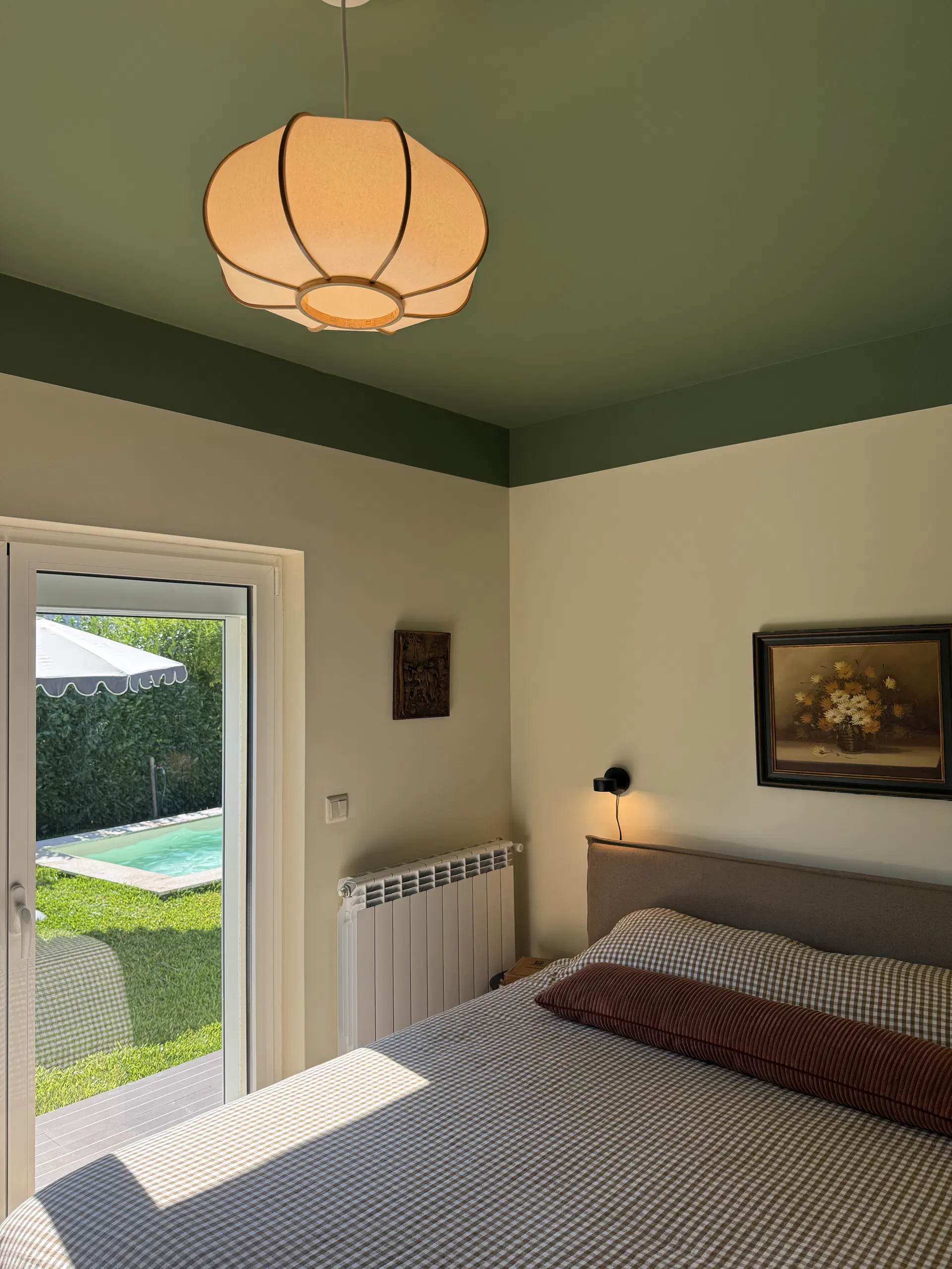 Cama de casal e portas de vidro abertas para o jardim no quarto de teto verde.