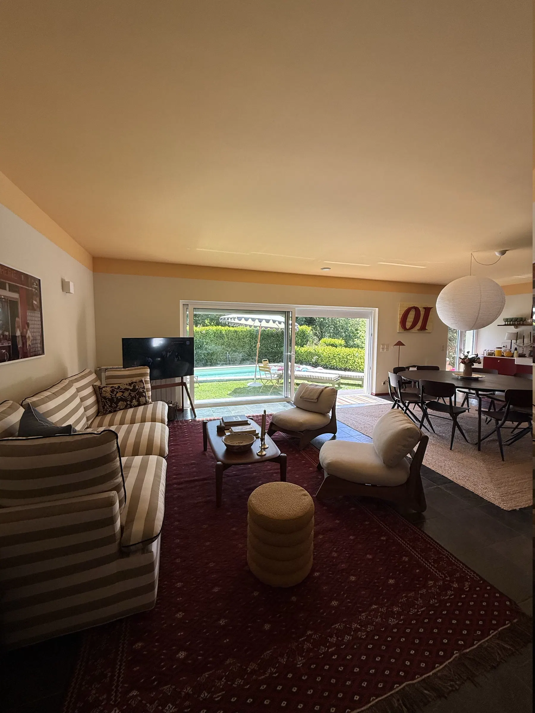 A sala e a zona de jantar com a piscina à vista pela janela — dentro e fora a viver juntos.