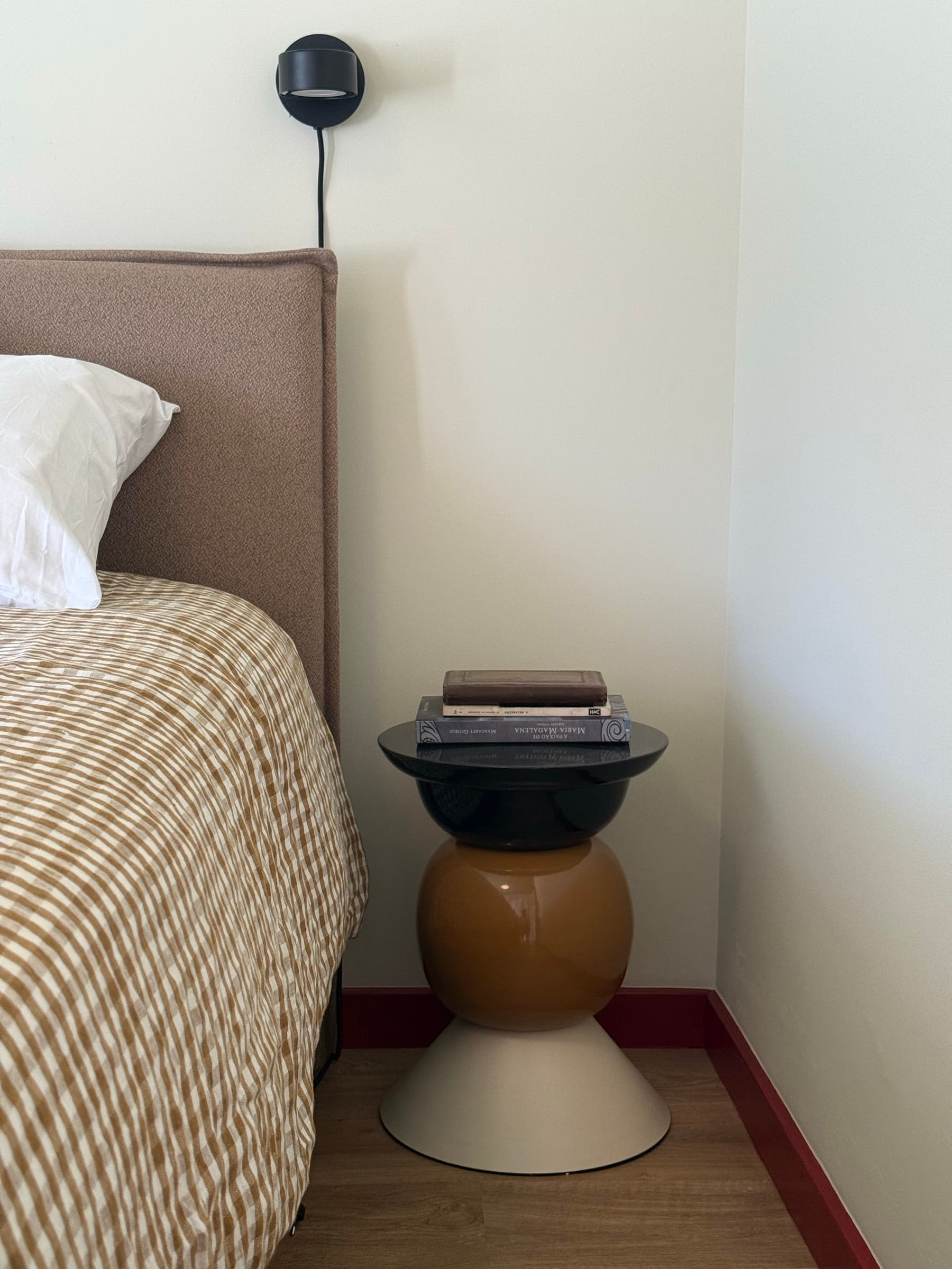 Quarto de casal com cabeceira estofada e roupa de cama aos quadrados em tons de ocre.