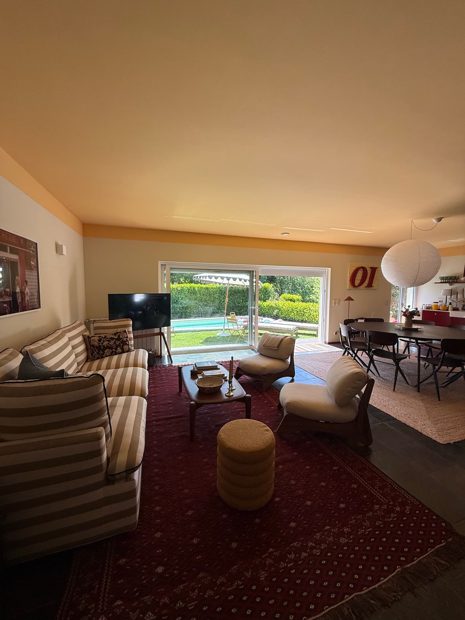 A sala e a zona de jantar com a piscina à vista pela janela — dentro e fora a viver juntos.